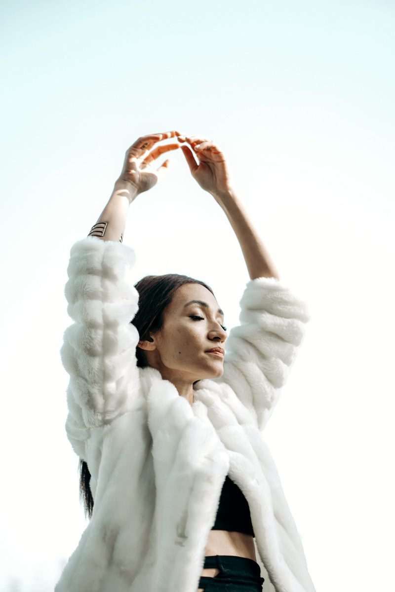 Mona Hassan, arms raised overhead in motion