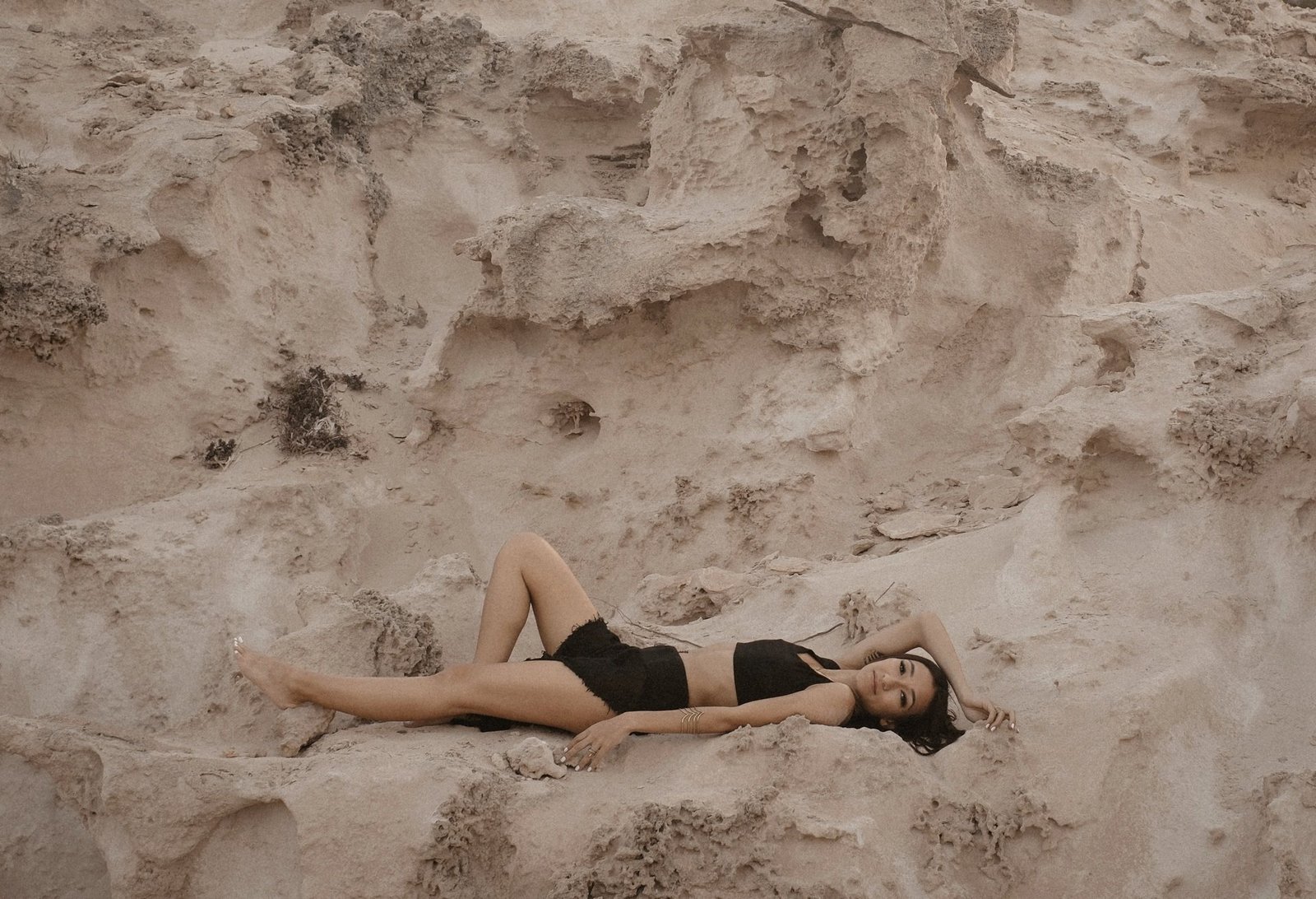 Mona Hassan lying across pale desert rock formations
