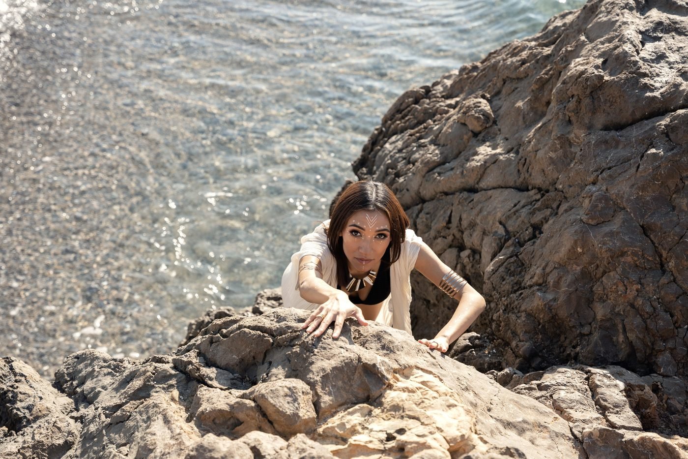 Mona Hassan climbing over coastal rocks, direct gaze